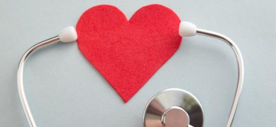 Stetoskop obejmujący słuchawkami serce wykonane z filcu.