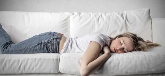 Kobieta cierpiąca na narkolepsję śpi na kanapie.