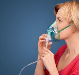 Kobieta używa nebulizatora do podania leku wziewnego.