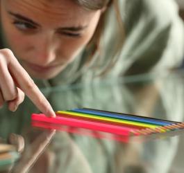 Kobieta z nerwicą natręctw układa kolorowe kredki w równym rzędzie.