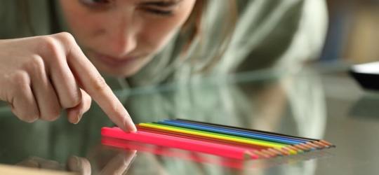 Kobieta z nerwicą natręctw układa kolorowe kredki w równym rzędzie.