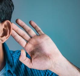 Mężczyzna cierpi na niedosłuch, nadstawia ucha, aby słyszeć lepiej.