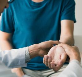 Lekarz sprawdza mężczyźnie puls na nadgarstku, by sprawdzić, czy ma wysokie lub niskie tętno.