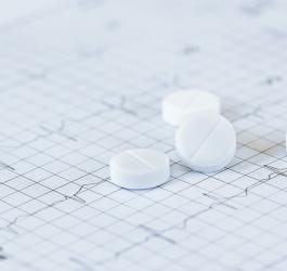 Tabletki nitrogliceryny na tle elektrokardiogramu.