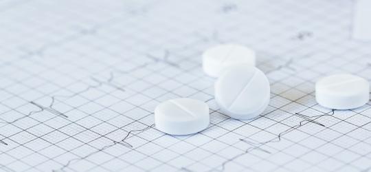 Tabletki nitrogliceryny na tle elektrokardiogramu.