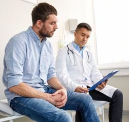 Mężczyzna w gabinecie lekarskim, rozmawia z urologiem na temat obrzezania.