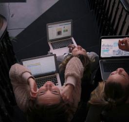 Kobiety wykonujące pracę na laptopach, siedzą na schodach.