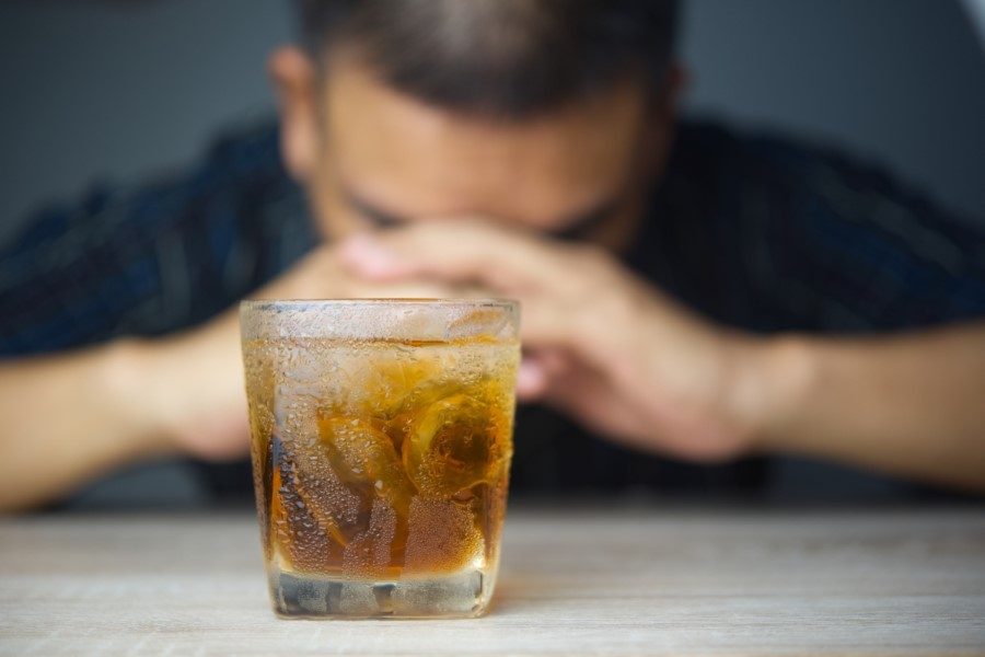 Szklanka z alkoholem, w tle mężczyzna.