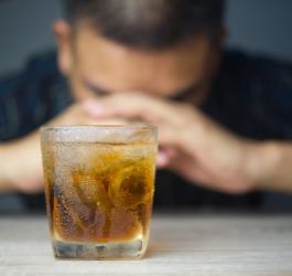 Szklanka z alkoholem, w tle mężczyzna.