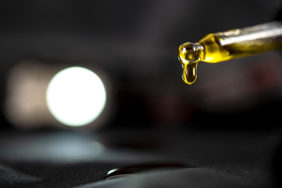 Kropla olejku CBD wypływająca z pipety.