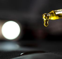 Kropla olejku CBD wypływająca z pipety.