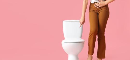 Kobieta wskazuje palcem na toaletę.