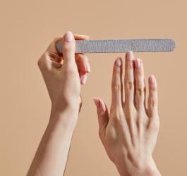Kobieta piłuje paznokcie przy pomocy papierowego pilniczka.