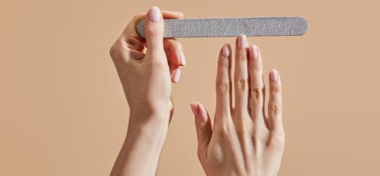 Kobieta piłuje paznokcie przy pomocy papierowego pilniczka.