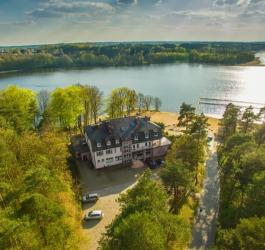 Budynek nad jeziorem, w okolicy las.