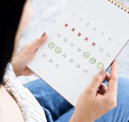 Kobieta sprawdza w kalendarzu, kiedy wystąpi jej owulacja i dni płodne.