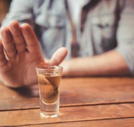 Mężczyzna odmawia sięgnięcia po kieliszek alkoholu.