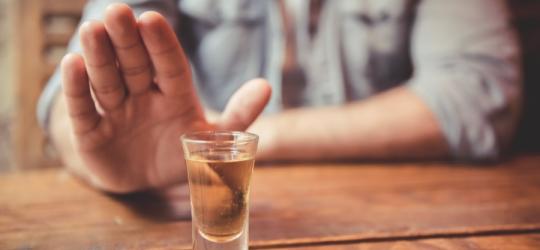 Mężczyzna odmawia sięgnięcia po kieliszek alkoholu.
