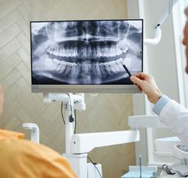 Dentysta pokazuje pacjentce zdjęcie panromograficzne jej twarzoczaszki.