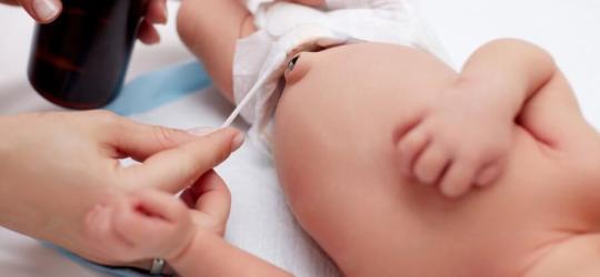 Mama pielęgnuje kikut pępowinowy u noworodka.