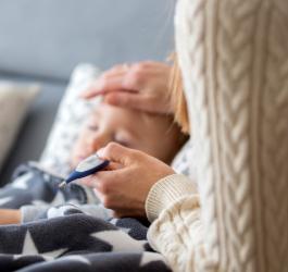 Mama mierzy temperaturę dziecku, które choruje na płonicę.