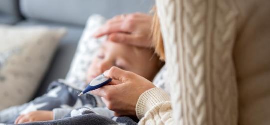 Mama mierzy temperaturę dziecku, które choruje na płonicę.