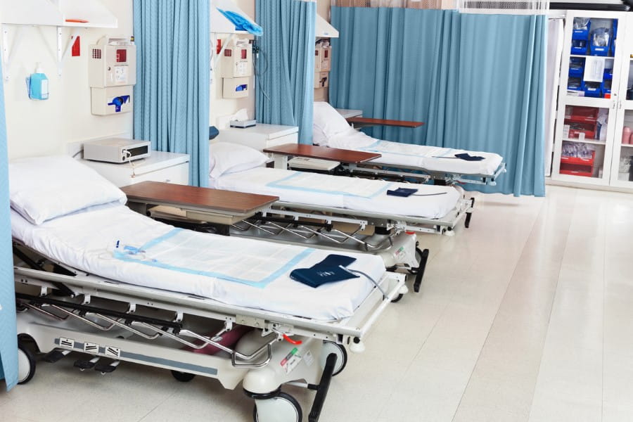 Łóżka na oddziale szpitalnym. Na materacach wyłożone są podkłady higieniczne.