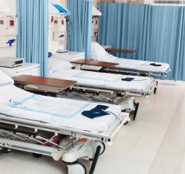 Łóżka na oddziale szpitalnym. Na materacach wyłożone są podkłady higieniczne.
