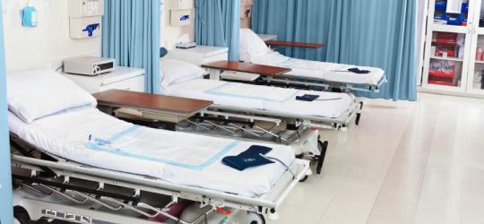 Łóżka na oddziale szpitalnym. Na materacach wyłożone są podkłady higieniczne.