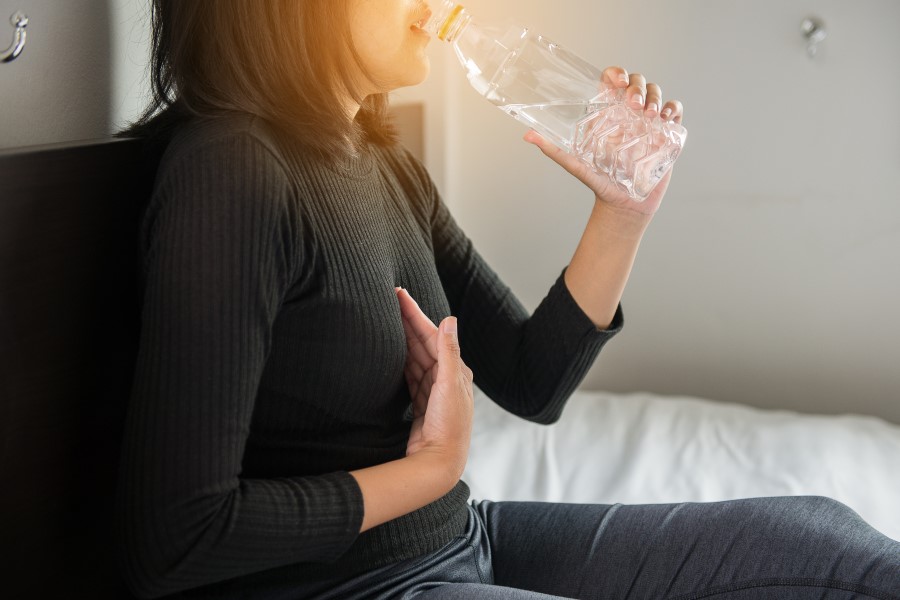 Kobieta cierpi na przepukline rozworu przelykowego, pije wodę.