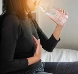 Kobieta cierpi na przepukline rozworu przelykowego, pije wodę.