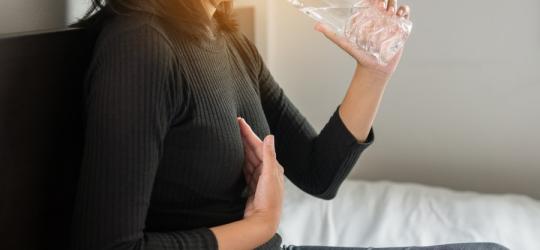 Kobieta cierpi na przepukline rozworu przelykowego, pije wodę.