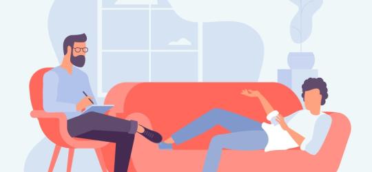 Grafika 2D. Pacjent siedzi na sofie podczas sesji u psychoterapeuty, który uważnie słucha i notuje.