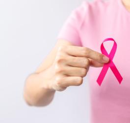 Kobieta ma w dłoni różową wstążeczkę – symbol walki z rakiem piersi.