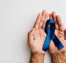 Mężczyzna trzyma w dłoniach niebieską wstążkę — symbol walki z rakiem prostaty.