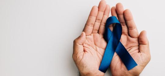 Mężczyzna trzyma w dłoniach niebieską wstążkę — symbol walki z rakiem prostaty.