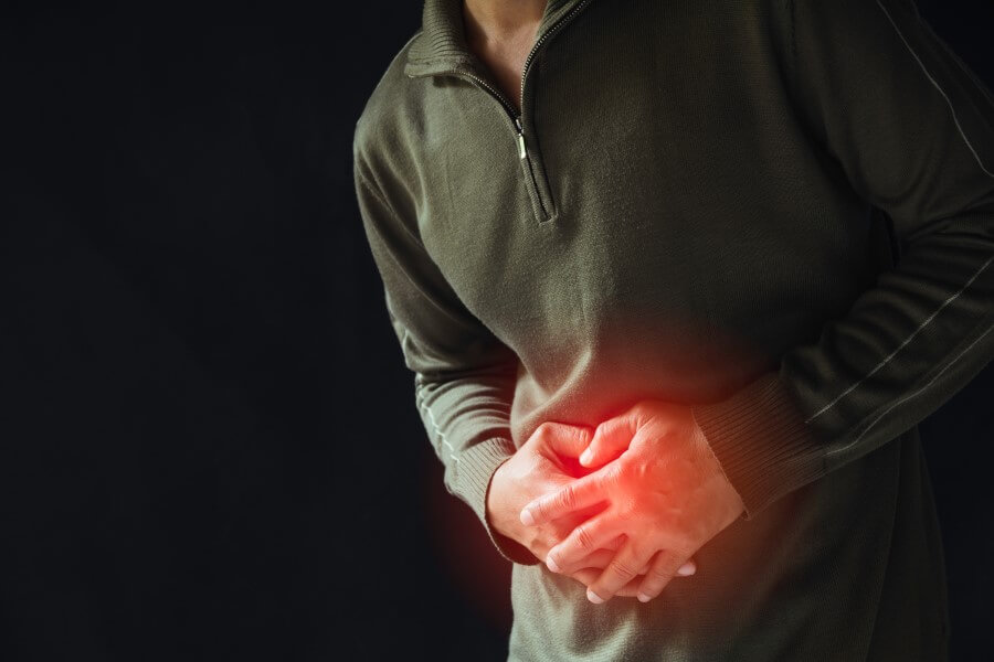 Mężczyzna trzyma się za bolesny brzuch, cierpi na raka żołądka.