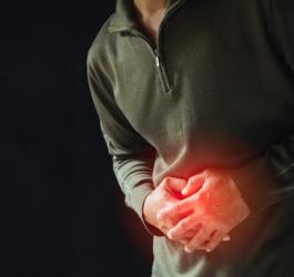 Mężczyzna trzyma się za bolesny brzuch, cierpi na raka żołądka.