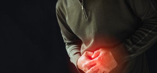 Mężczyzna trzyma się za bolesny brzuch, cierpi na raka żołądka.