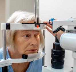 Starsza kobieta podczas badania wzroku w gabinecie okulistycznym.