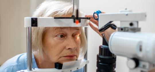 Starsza kobieta podczas badania wzroku w gabinecie okulistycznym.