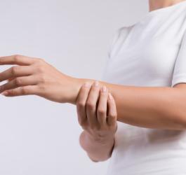 Kobieta trzyma się za przedramię.