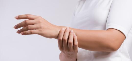 Kobieta trzyma się za przedramię.