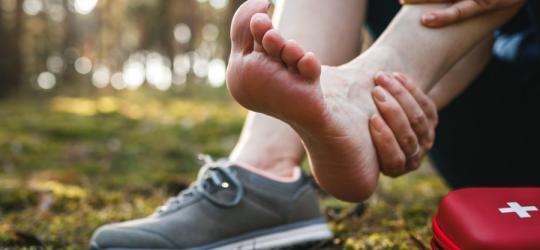 Kobieta skręciła kostkę podczas treningu na świeżym powietrzu. Skręcona kostka wymaga opatrzenia.