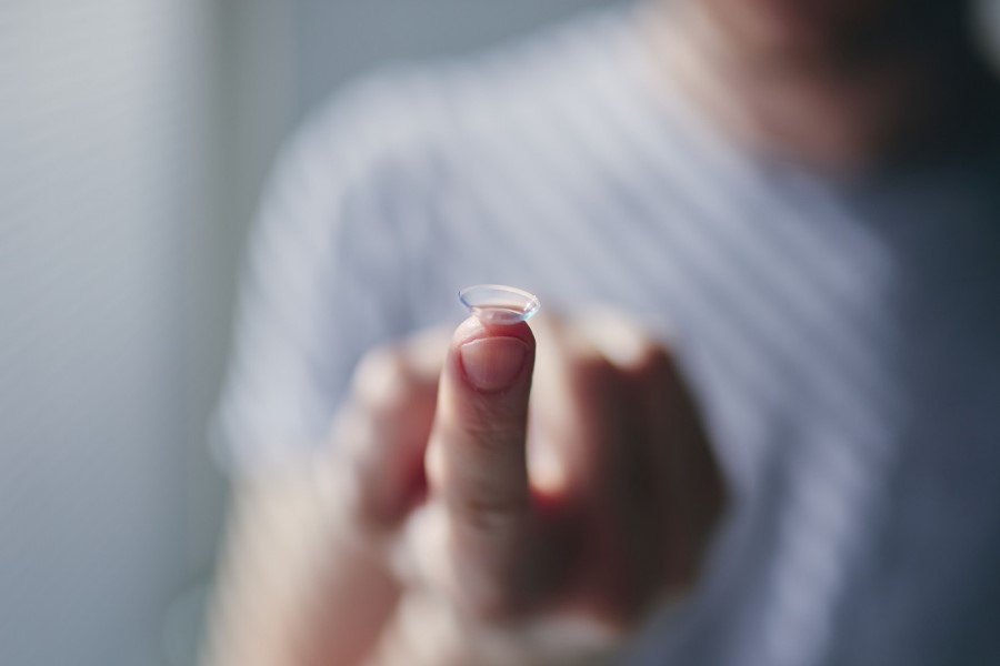 Mężczyzna trzyma na opuszku palca soczewkę korekcyjną.