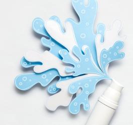 Biała buteleczka z wyciętą z papieru dekoracją w kształcie rozbryzgów wody.