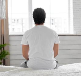 Zmartwiony zaburzeniami erekcji mężczyzna siedzi na skraju łóżka.