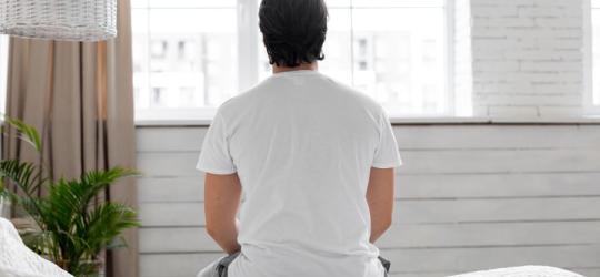 Zmartwiony zaburzeniami erekcji mężczyzna siedzi na skraju łóżka.