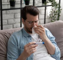 Mężczyzna mierzy sobie temperaturę i sprawdza, czy ma stan podgorączkowy czy już gorączkę.