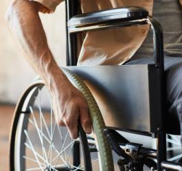 Mężczyzna porusza się na wózku, cierpi na stwardnienie zanikowe boczne.